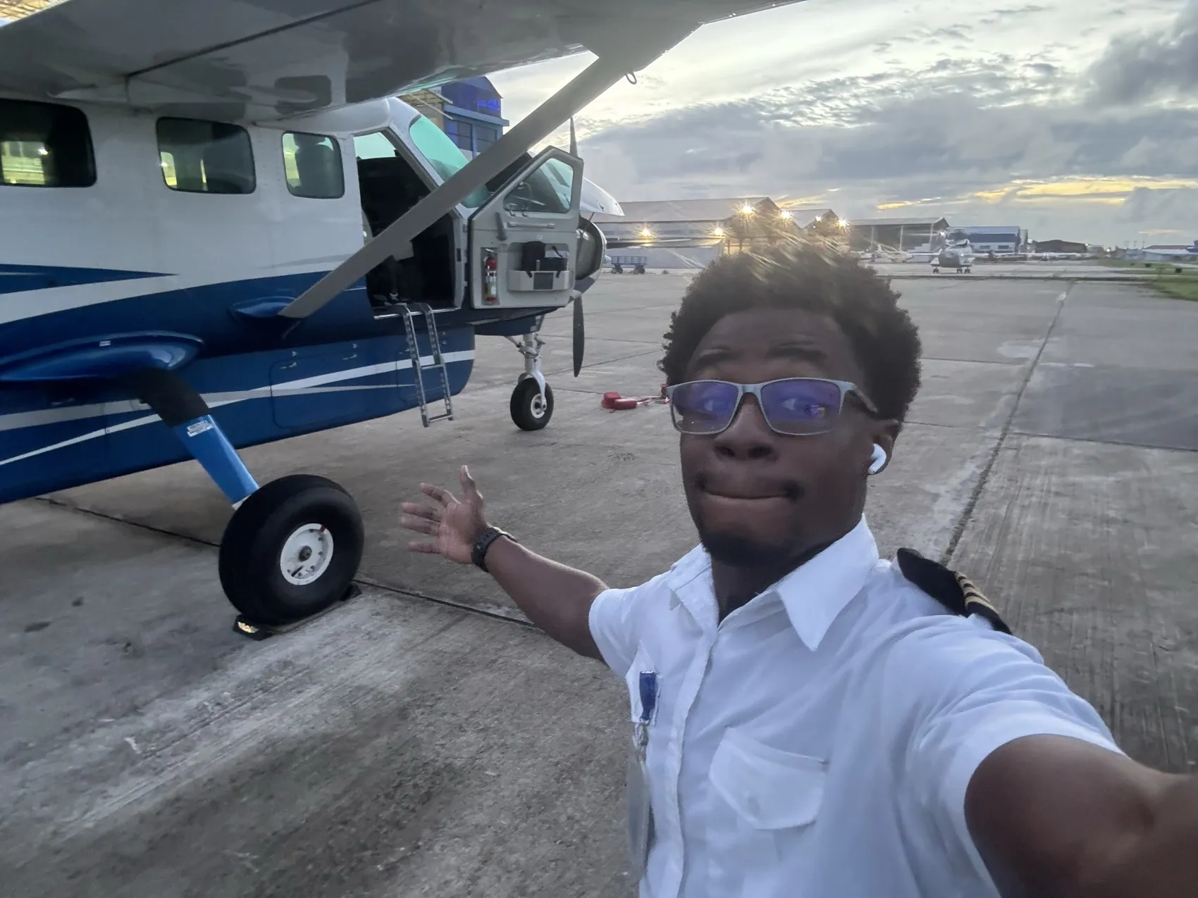Michael A. Thom in aviation uniform beside a Cessna Caravan, Guyana