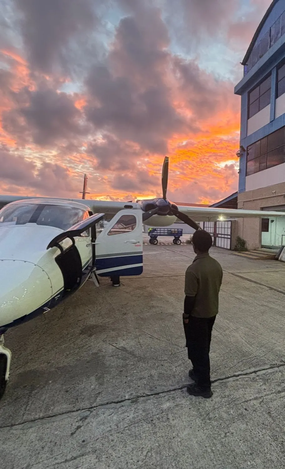 Michael A. Thom facing an aircraft at dusk in Georgetown, Guyana